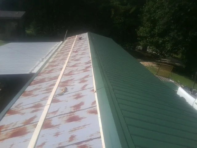 Old rusted panels beside newly installed green metal roofing — Wind Damage Roof Repair by Roofing Brothers in Coeur d'Alene