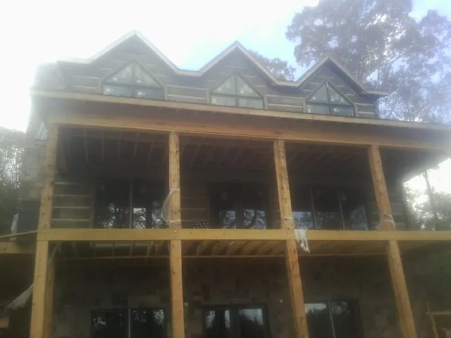 Dormers and porch framing on a large log home under construction — Roof Coating work by our crew in Coeur d'Alene