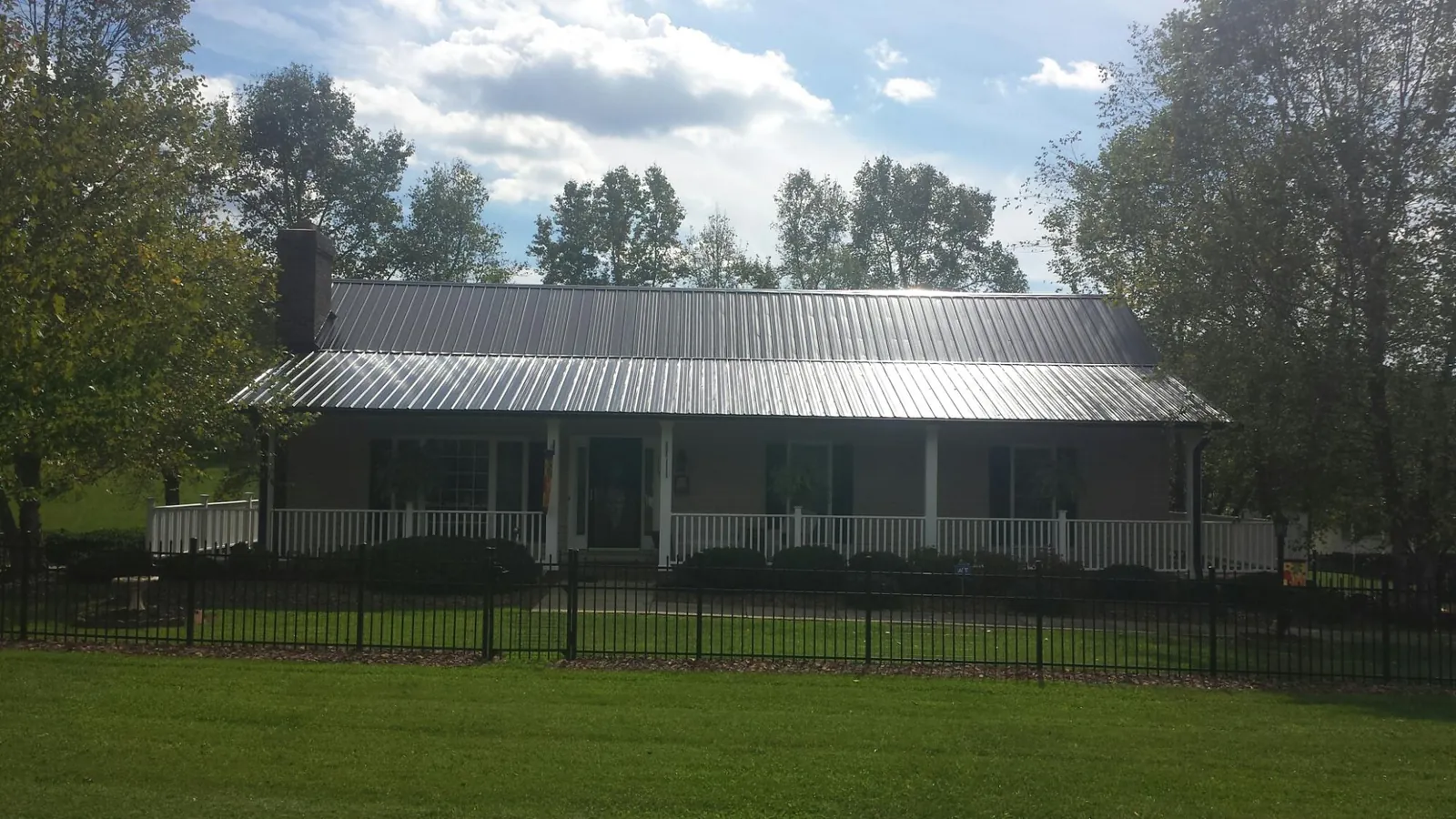 Gray metal roof on a brick ranch with a full width front porch — Gutter Guard Installation work by our crew in Coeur d'Alene