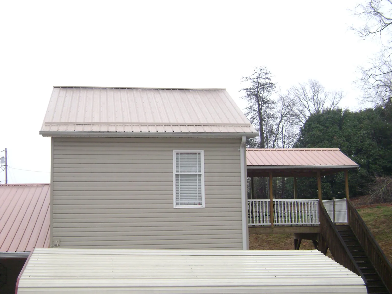 Tan metal roofs on a two story addition and attached porch, from a Roof Replacement job in Coeur d'Alene