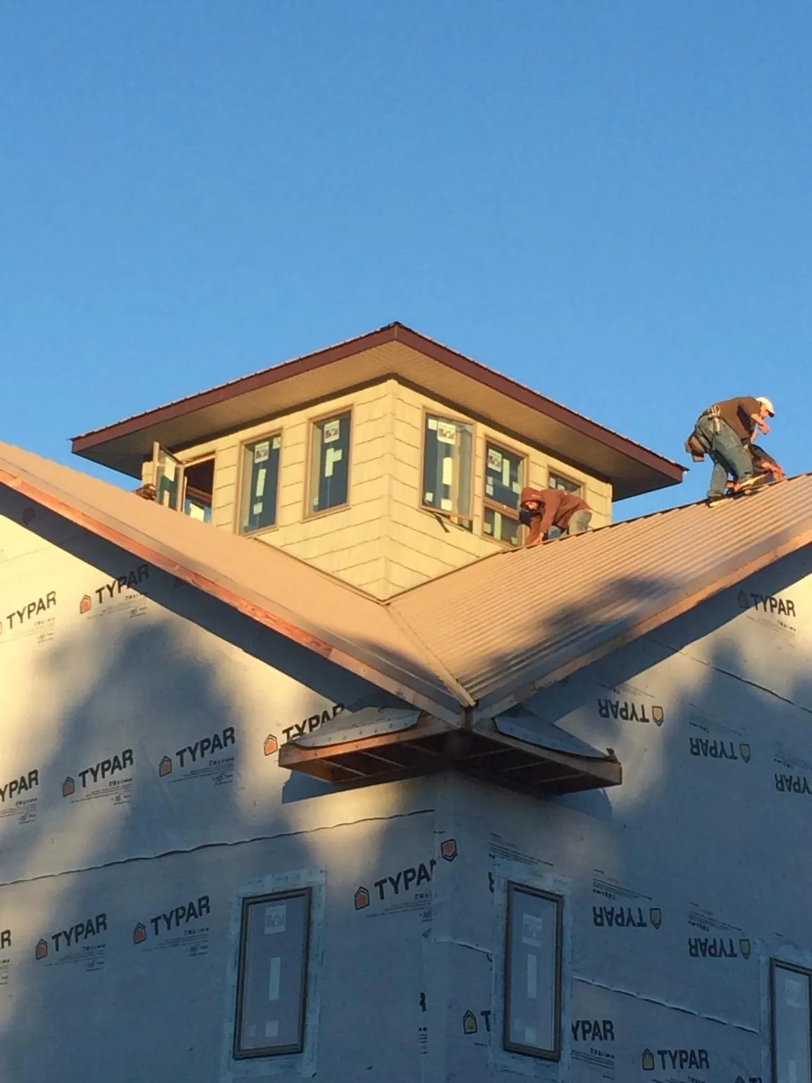 Roofers working around a rooftop cupola on a new metal roof at sunset — Roof Waterproofing in Coeur d'Alene by Roofing Brothers